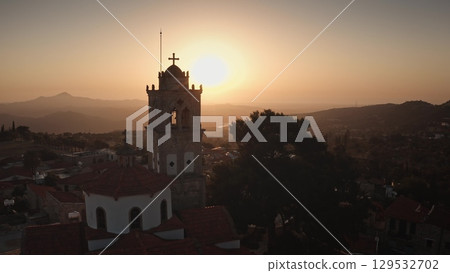 Cyprus: Warm sunset illuminates the bell tower of a church in a picturesque Cyprus village, creating a serene and spiritual atmosphere. Drone flight Cyprus: Warm sunset illuminates the bell tower of a church in a picturesque Cyprus village, creating a serene and spiritual atmosphere. Drone flight 129532702