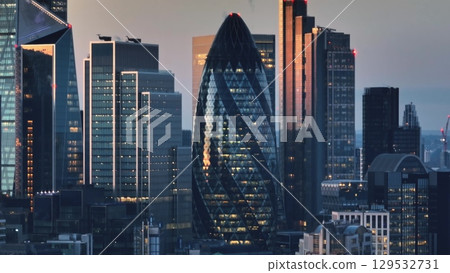 United Kingdom, London: Aerial view capturing the London skyline at sunset, highlighting modern skyscrapers and the iconic Gherkin amidst the cityscape. Drone flight 129532731