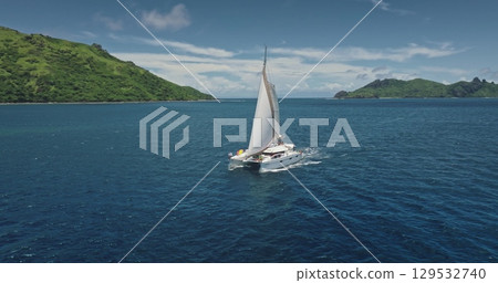 Luxurious catamaran sailing in the pristine waters of Fiji, near Kuata island, offering a breathtaking view of the tropical landscape and the vastness of the Pacific Ocean. Drone flight 129532740