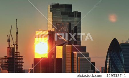 Modern glass skyscrapers in London financial district at golden hour. Sunset light reflecting on glass facades of buildings. Cityscape skyline background. Panorama shot 129532741