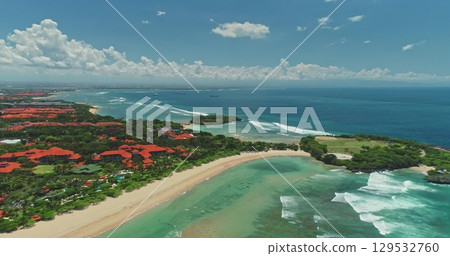 Aerial drone of Nusa Dua beach with luxury hotels, white sand, turquoise water and waves meeting the blue of the Indian Ocean, Bali, Indonesia, on a sunny day with some clouds 129532760