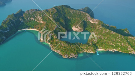 Breathtaking aerial view revealing Mae Ko island in Ang Thong National Marine Park, Thailand, featuring lush vegetation, a hidden lagoon, and vibrant turquoise waters 129532763