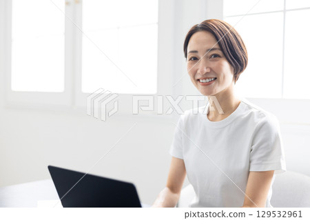 A woman teleworking using a laptop in a bright home 129532961