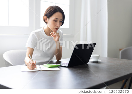 A woman teleworking using a laptop in a bright home A woman teleworking using a laptop in a bright home 129532970
