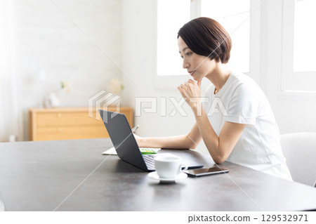 一位女士在明亮的家中使用筆記型電腦進行遠距辦公 129532971