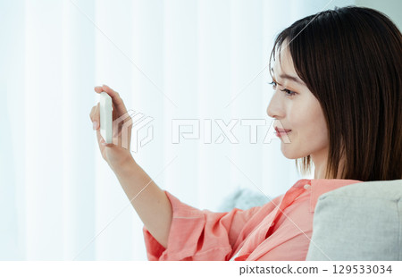 A young woman operating a smartphone 129533034