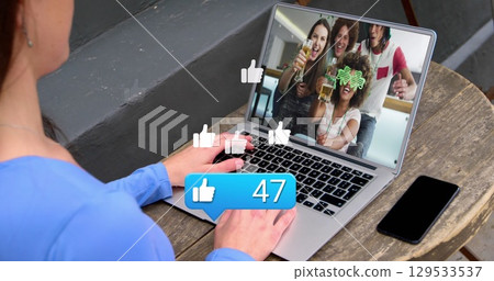 Like icon with increasing numbers over caucasian woman having a imagecall on laptop at a cafe 129533537