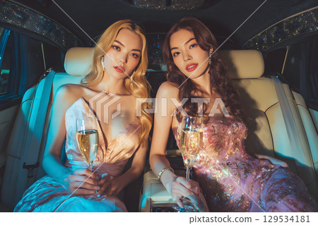 兩位年輕、名媛般的女性在豪華轎車裡舉杯慶祝，度過了一個迷人的夜晚 129534181