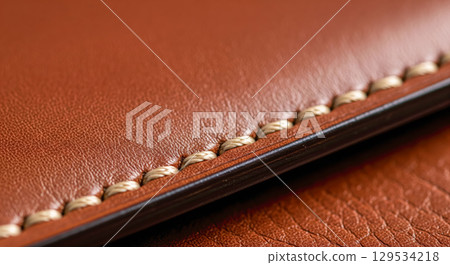 Macro closeup of brown leather texture with neat stitching. Concept of handmade craftsmanship, quality materials and luxury goods with fine expensive details Macro closeup of brown leather texture with neat stitching. Concept of handmade craftsmanship, quality materials and luxury goods with fine expensive details 129534218