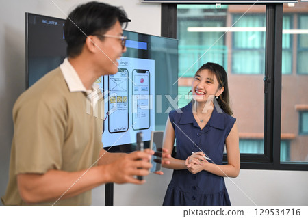 Creative team members exchanging ideas and presenting UI design concepts in a modern office 129534716