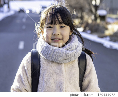 A smiling elementary school girl on her way to school in winter (Japanese model, randoseru) 129534972