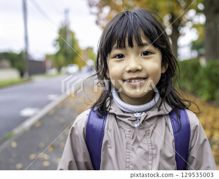 A smiling elementary school girl on her way to school in autumn (Japanese model, randoseru) 129535003