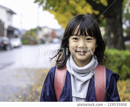 A smiling elementary school girl on her way to school in autumn (Japanese model, randoseru) 129535008