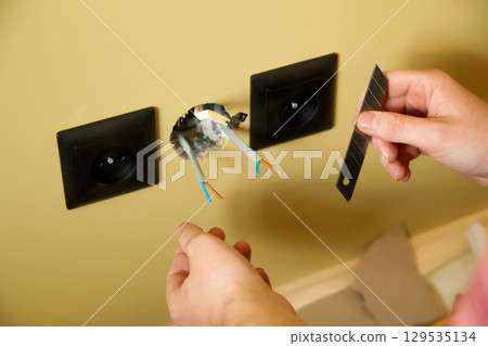 an electrician making a precise cut with a knife. The photo, with a focus on the man's hand, is perfect for a theme of wiring and circuits for a modern installation 129535134
