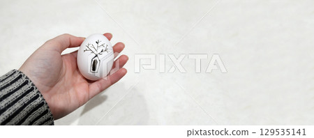 banner with a hand holding a beautiful pysanka Easter egg. The egg, with its intricate black and white pattern and a touch of drawing, represents a timeless tradition from Ukraine banner with a hand holding a beautiful pysanka Easter egg. The egg, with its intricate black and white pattern and a touch of drawing, represents a timeless tradition from Ukraine 129535141