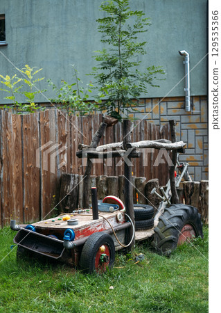 Homemade toy tractor made from wood, tires, and recycled parts in a grassy backyard playground. DIY playgrounds, sustainable play, creative reuse, eco-conscious parenting Homemade toy tractor made from wood, tires, and recycled parts in a grassy backyard playground. DIY playgrounds, sustainable play, creative reuse, eco-conscious parenting 129535366