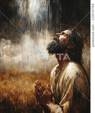 man long hair and beard kneels hands clasped in prayer. He faces sky as rain falls in golden field creating serene atmosphere dusk. 129535769