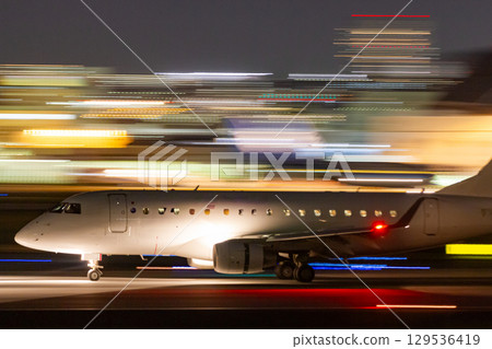 A small jet plane speeding through an airport at night 129536419