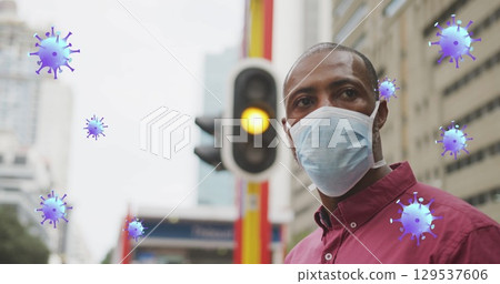 Image of virus cells over african american man wearing face mask 129537606