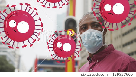 Image of falling covid 19 cells over african american man wearing face mask 129537609
