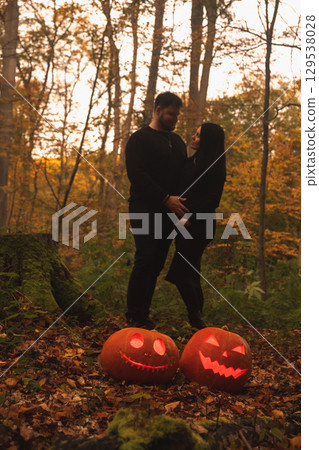 Couple in Autumn Forest with Halloween Pumpkins Couple in Autumn Forest with Halloween Pumpkins 129538028