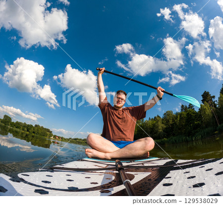 Man Taking Selfie on Paddleboard in Scenic Lake 129538029