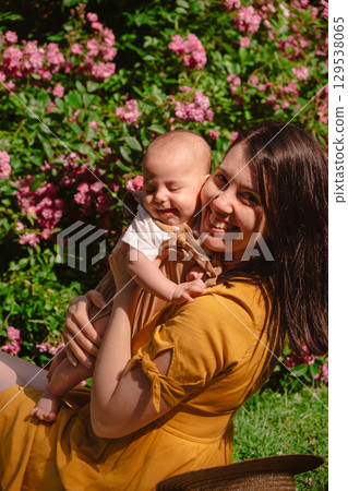 Joyful Mother and Baby in Blooming Garden 129538065
