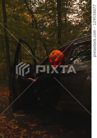 Autumn SUV with Driver with Pumpkin Head in Forest Autumn SUV with Driver with Pumpkin Head in Forest 129538077