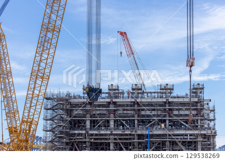 Construction site with construction crawler cranes and multi storey unfinished buildings, Many high rise cranes and industrial construction equipment, Contruction site bl;ue sky background. Construction site with construction crawler cranes and multi storey unfinished buildings, Many high rise cranes and industrial construction equipment, Contruction site bl;ue sky background. 129538269