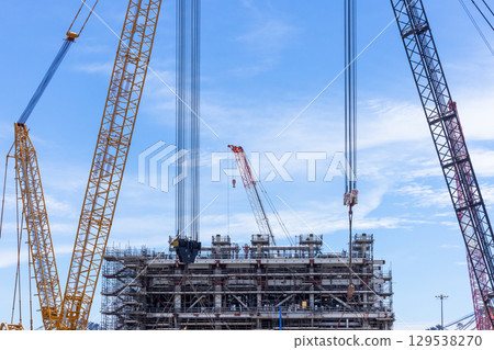 Construction site with construction crawler cranes and multi storey unfinished buildings, Many high rise cranes and industrial construction equipment, Contruction site bl;ue sky background. Construction site with construction crawler cranes and multi storey unfinished buildings, Many high rise cranes and industrial construction equipment, Contruction site bl;ue sky background. 129538270