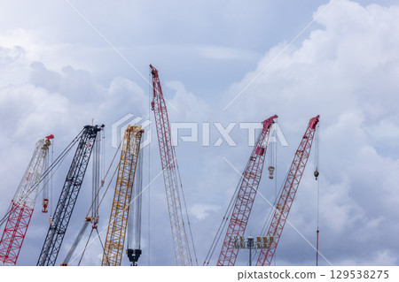 Crawler crane on blue sky white clouds background, Real estate industry. Red crawler crane use reel lift up equipment in construction site. Crane for rent. Crane dealership for construction business. Crawler crane on blue sky white clouds background, Real estate industry. Red crawler crane use reel lift up equipment in construction site. Crane for rent. Crane dealership for construction business. 129538275