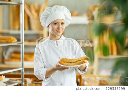 Young woman chef of pastry shop demonstrates product of assortment, bocadillo on disposable plates Young woman chef of pastry shop demonstrates product of assortment, bocadillo on disposable plates 129538299