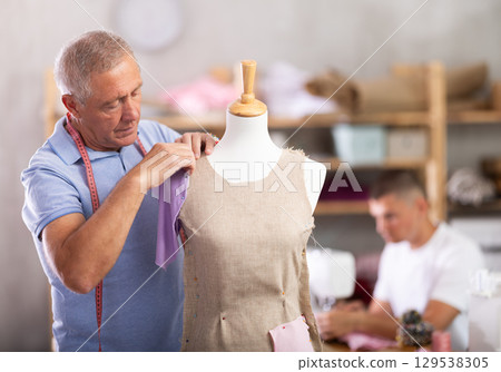 Mature tailor working with mannequin against the background of specialist 129538305
