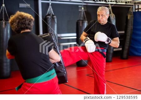 Man punches boxing paw held by trainer Man punches boxing paw held by trainer 129538595