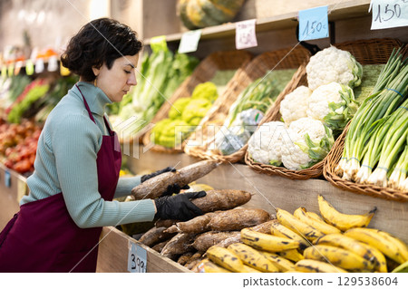 Woman shop seller puts cassava goods on display case Woman shop seller puts cassava goods on display case 129538604