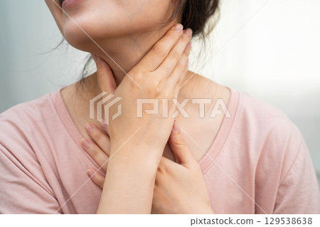 Asian woman touching her neck and throat for thyroid gland problem. 129538638