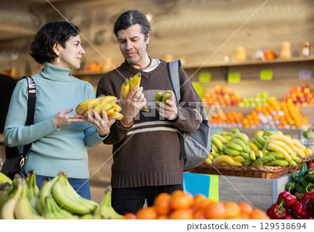 Married couple chooses bananas and other fruits at supermarket counter Married couple chooses bananas and other fruits at supermarket counter 129538694