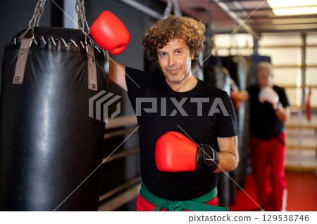 Strong man practicing punches on punching bag. Boxing training Strong man practicing punches on punching bag. Boxing training 129538746
