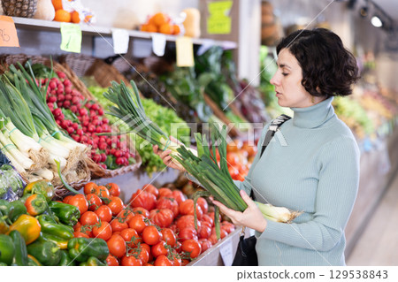 Adult woman choosing green onions in vegetable shop Adult woman choosing green onions in vegetable shop 129538843