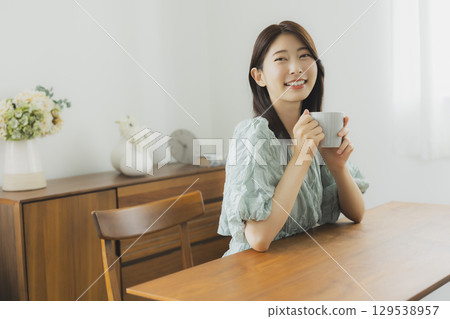年輕女子在房間裡喝咖啡 129538957