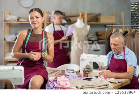 Girl fashion designer is in office, senior man sewing clothes, guy work with mannequin in background 129538964