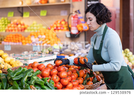 Woman shop seller puts tomato goods on display case Woman shop seller puts tomato goods on display case 129538976