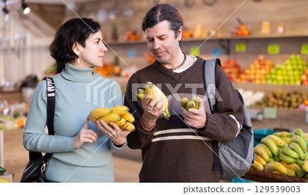 Married couple chooses bananas and other fruits at supermarket counter Married couple chooses bananas and other fruits at supermarket counter 129539003