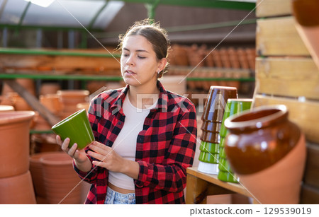Portrait of woman choosing pots for flowers in gardening market Portrait of woman choosing pots for flowers in gardening market 129539019