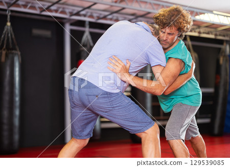 Middle aged man practicing close combat wrestling Middle aged man practicing close combat wrestling 129539085