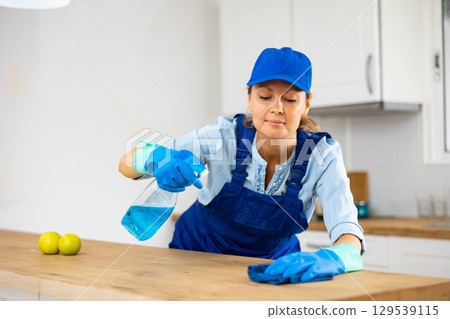 Skilled woman house cleaner sanitizing kitchen countertop Skilled woman house cleaner sanitizing kitchen countertop 129539115