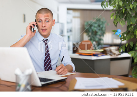 Male clerical worker having telephone conversation 129539131