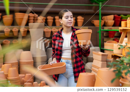 Portrait of woman choosing pots for flowers in gardening market Portrait of woman choosing pots for flowers in gardening market 129539152