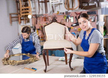 Girl restoration worker dressed in overalls poses in working atmosphere of his workshop Girl restoration worker dressed in overalls poses in working atmosphere of his workshop 129539155