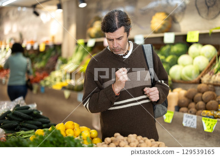Male shopper carefully selects fresh bananas in grocery supermarket 129539165